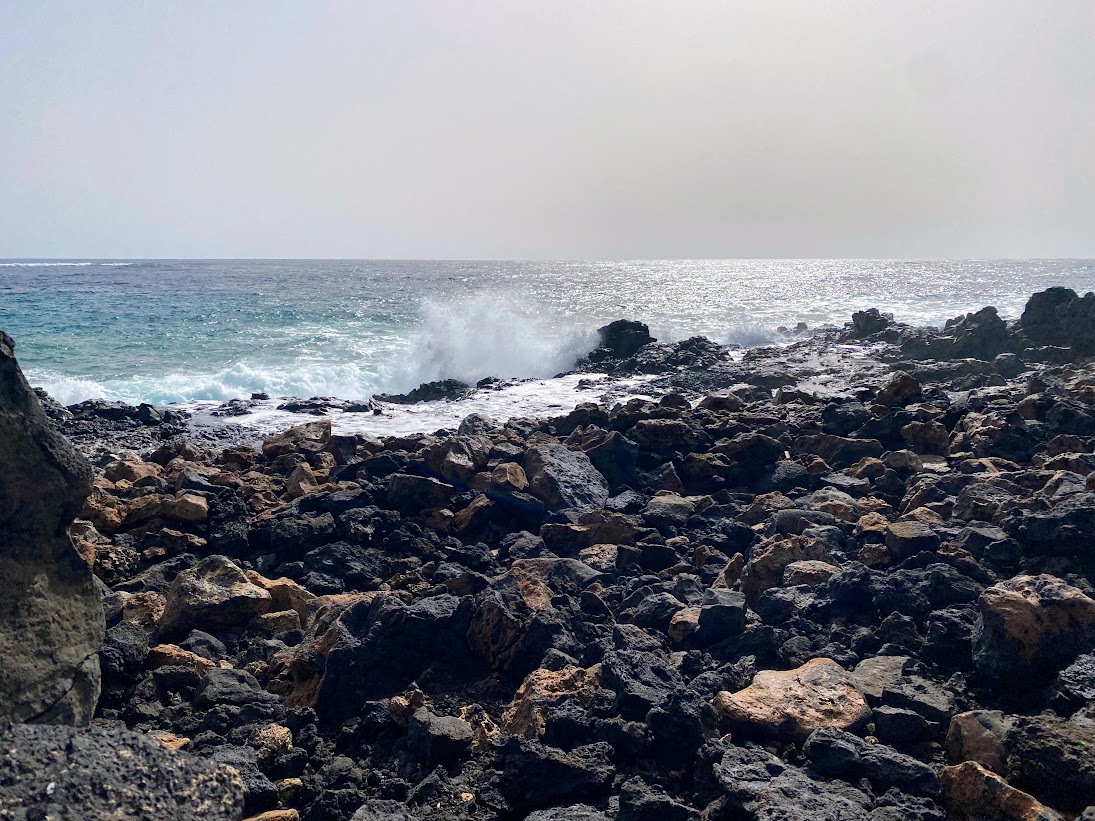 Black rocks with grey beach and sky
